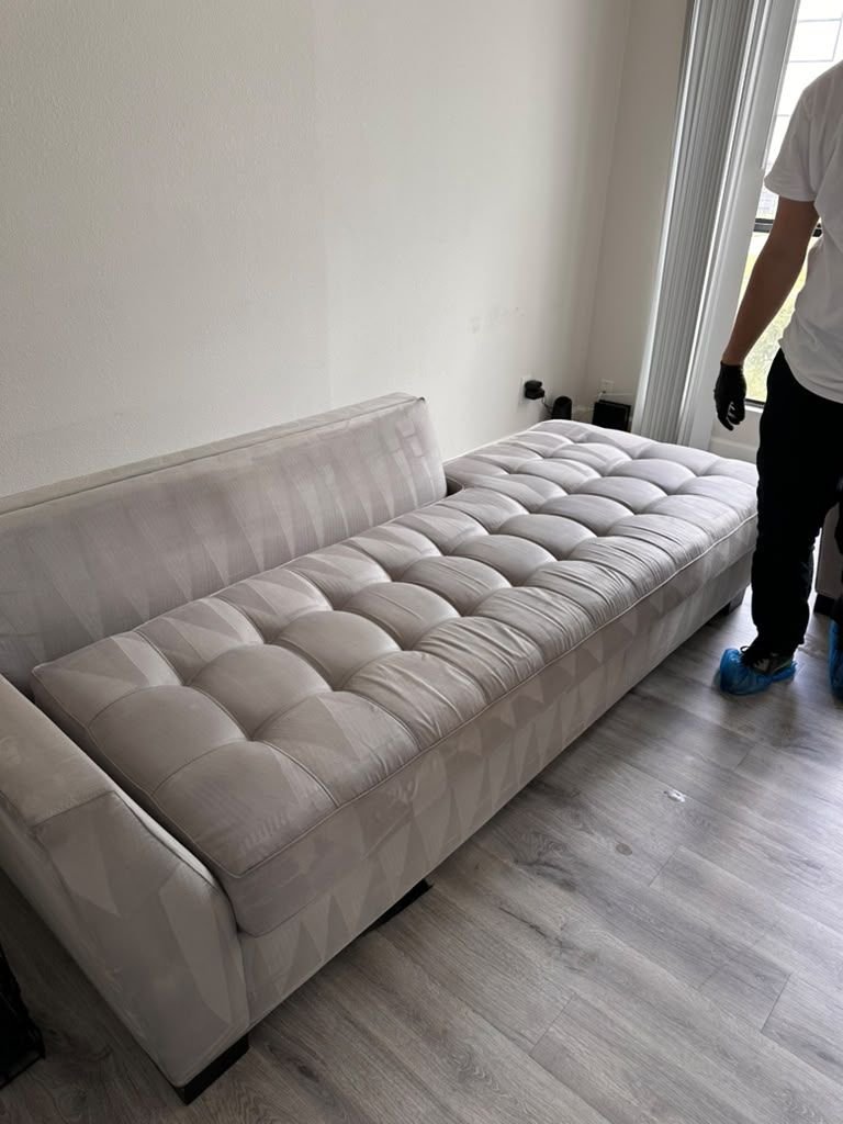 A light gray tufted sofa with even, freshly cleaned cushions
