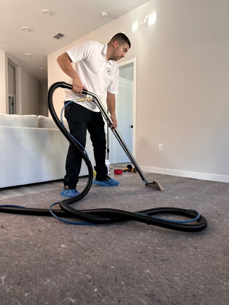 A Magic Steam technician extracting a carpeted living room with a wand and floor protection