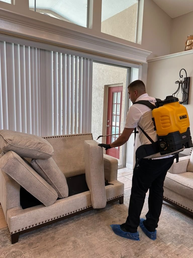 A Magic Steam technician cleaning a sofa with a backpack extractor and wand